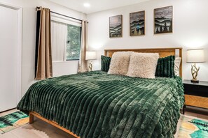 A neatly made bed with a green textured bedspread, two fluffy pillows, and a wooden headboard. - Walkable Condo Near Ski Shuttle & Mammoth Creek! (Mammoth Lakes)