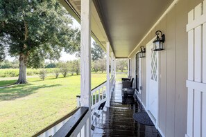 Eine überdachte Veranda mit Blick auf eine grüne Landschaft und Bäume.