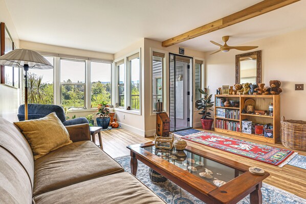 A cozy living room with a sofa, coffee table, and a bookshelf filled with books and decorative items.