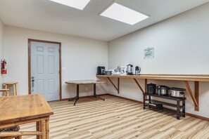 A room with a wooden table, a small stool, a white door, and a shelf with kitchen appliances. - 1 Block to Private Key Entry Beach (Bellingham)