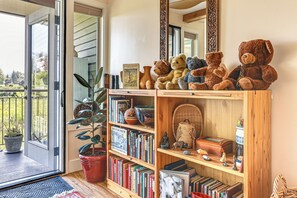 A room with a bookshelf filled with books, a potted plant, and a collection of teddy bears.