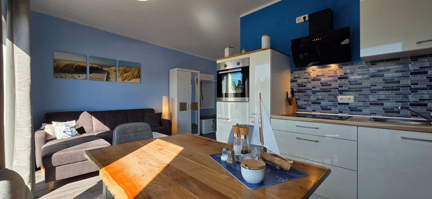 A compact living space with a kitchenette, a dining area with a wooden table, and a sofa.