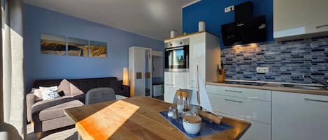 A compact living space with a kitchenette, a dining area with a wooden table, and a sofa.