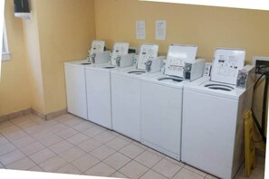 A row of white washing machines in a room with yellow walls and tiled flooring. - 2 Full Beds | Non-Smoking, Micfridge (Myrtle Beach SC)