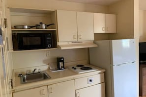 Une petite cuisine équipée d’un four à micro-ondes, d’une cuisinière, d’un évier et d’un réfrigérateur.