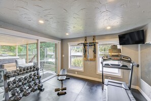 A home gym with exercise equipment, a bench, and a TV mounted on the wall. - Waterfront Living on Lake St Clair with Sauna (Olympia)