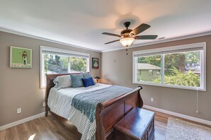 Une chambre à coucher avec un lit, un ventilateur de plafond et deux fenêtres.