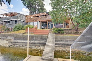 A waterfront property with a wooden deck leading to a house with a covered porch and a hot tub. - Waterfront Living on Lake St Clair with Sauna (Olympia)