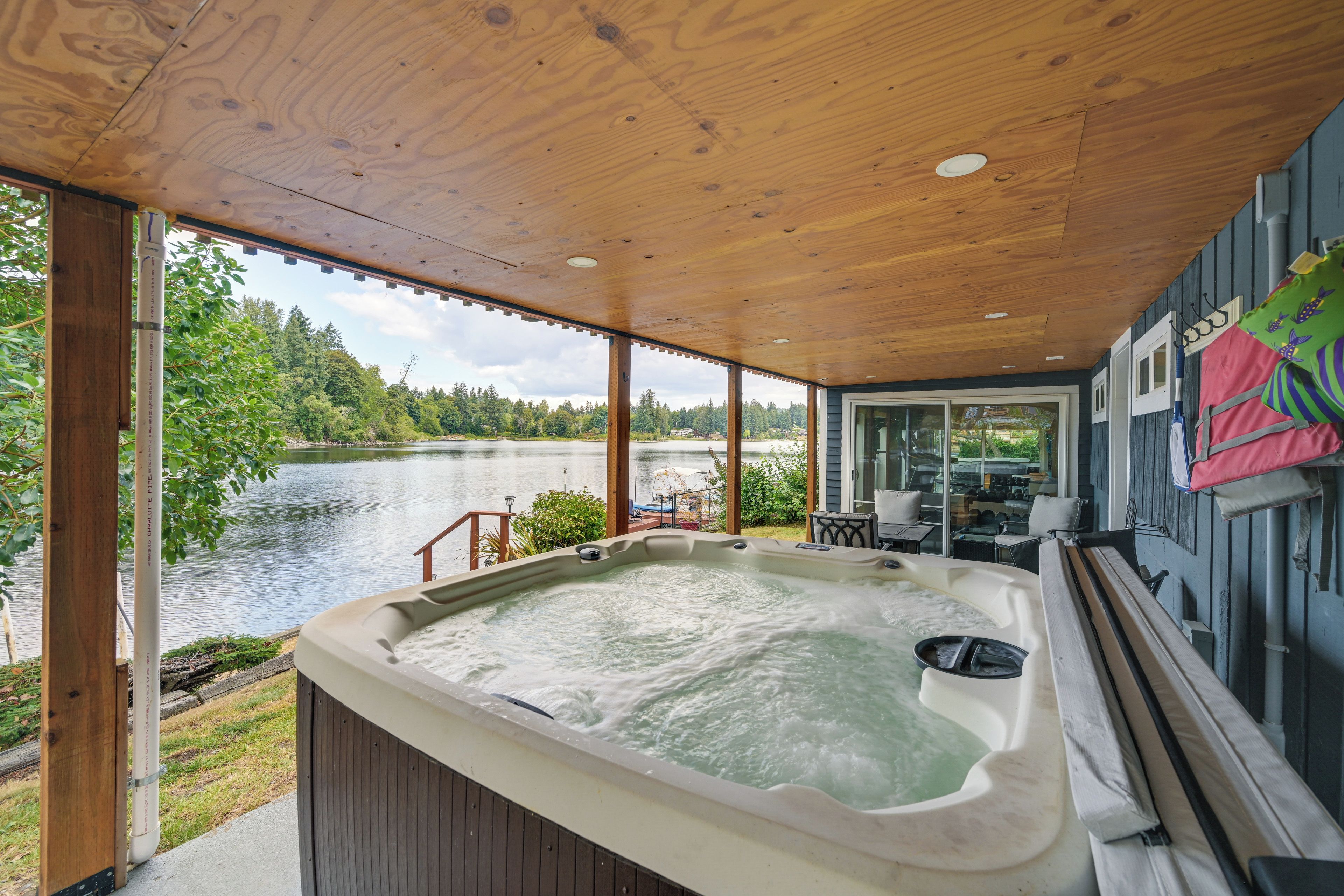 A hot tub with a wooden deck and a view of a lake.