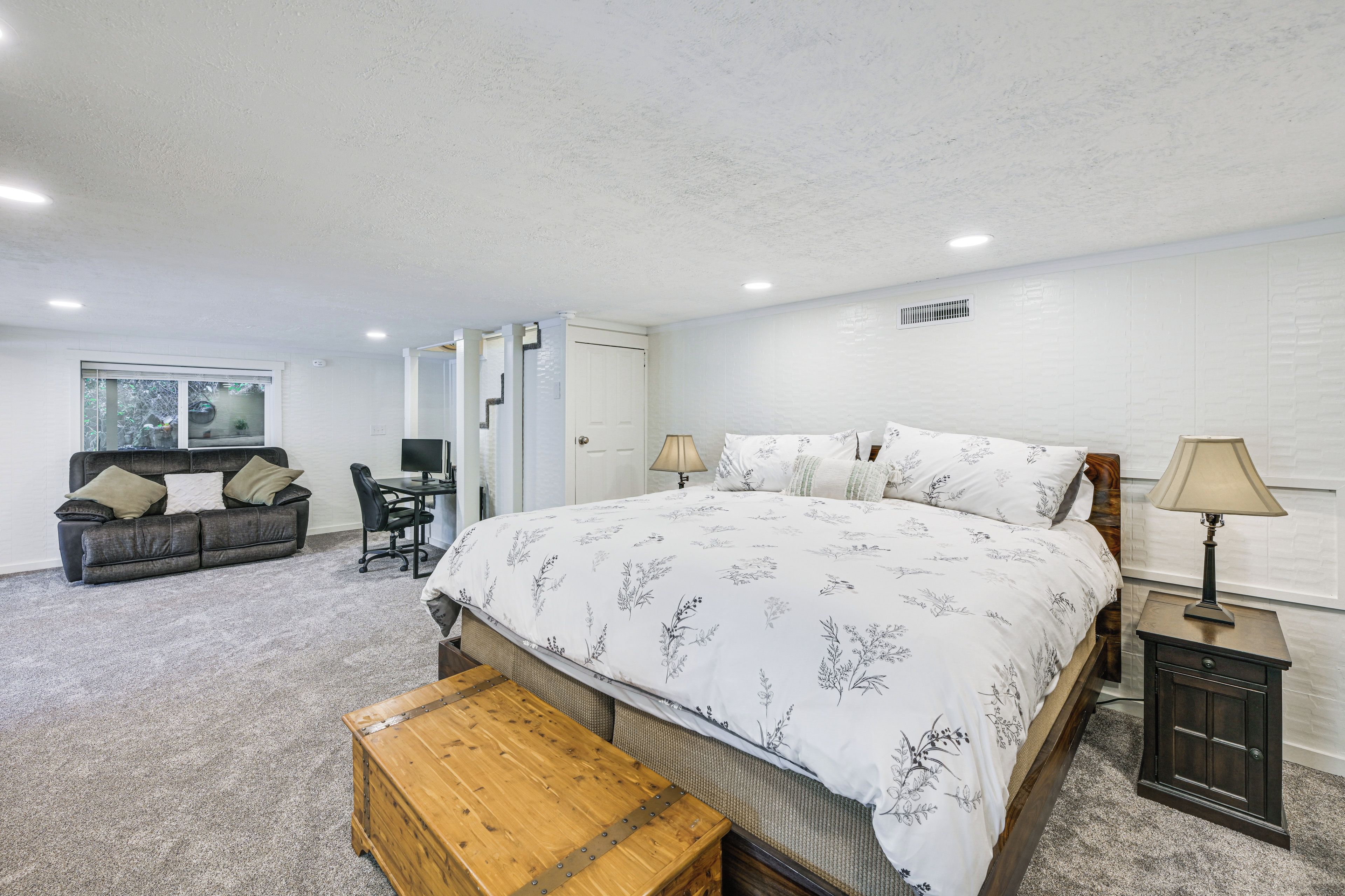 Une chambre avec un grand lit, un bureau, une chaise et un canapé.