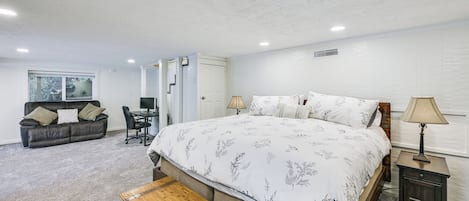 Une chambre avec un grand lit, un bureau, une chaise et un canapé.
