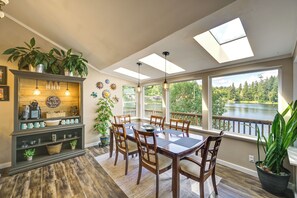 A dining area with a wooden table and chairs, a coffee bar, and large windows with a view of a lake. - Waterfront Living on Lake St Clair with Sauna (Olympia)