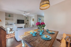 Un comedor con una mesa de madera, sillas y un florero con flores.