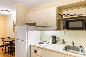 A compact kitchen with a refrigerator, stove, microwave, and a coffee maker. - 1 King Bed | Non-Smoking, Micfridge, Sofa-Bed (Myrtle Beach SC)