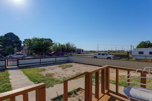 A fenced outdoor area with a wooden deck, a bench, and a clear sky.