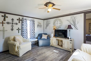 A living room with a ceiling fan, a TV, a couch, a chair, and a cabinet.