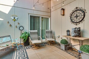 Une terrasse dotée d’une porte-fenêtre coulissante, d’une chaise en métal, d’un banc, d’une petite table avec une lanterne, ainsi que d’éléments décoratifs sur les murs, notamment une horloge et des décorations sur le thème des abeilles.