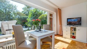 Ein modernes Wohnzimmer mit einem weißen Tisch, zwei Stühlen, einem Fernseher und einer Heizung.