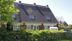 Ein zweistöckiges Haus mit geneigtem Dach und einer Steinmauer, mit dem Schild 'Malvenhof'.
