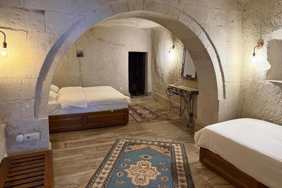 A room with a stone archway, a bed, a bedside table, and a rug.