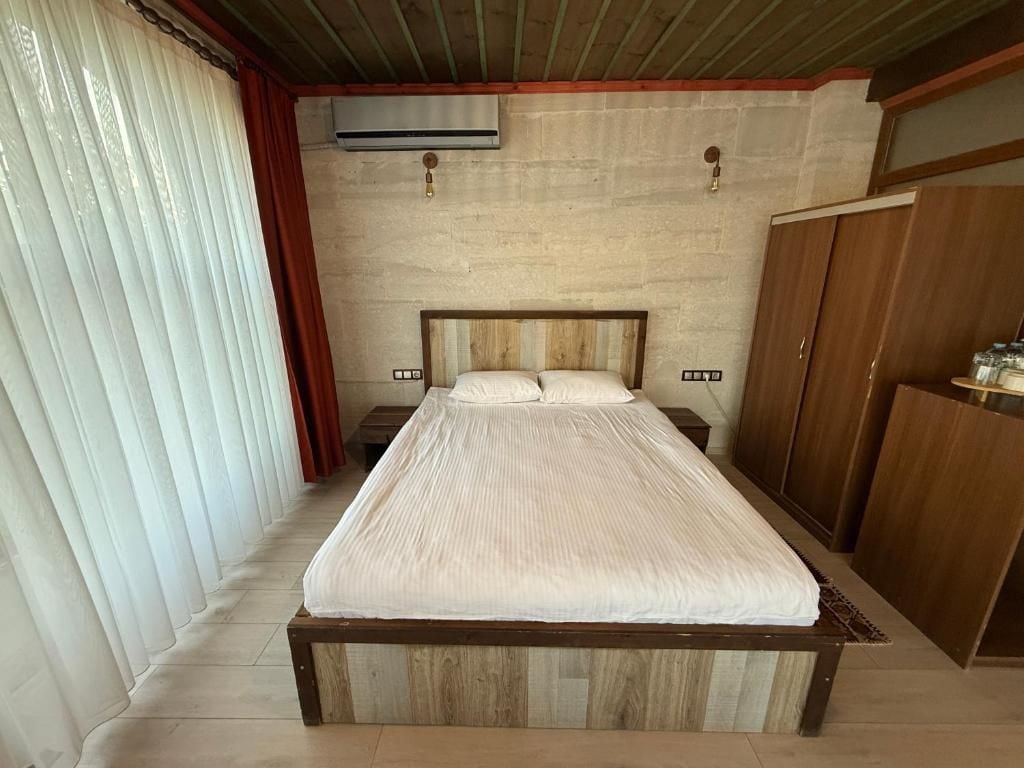 A bedroom with a wooden bed, a wardrobe, and a wall-mounted air conditioner.