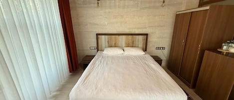 A bedroom with a wooden bed, a wardrobe, and a wall-mounted air conditioner.