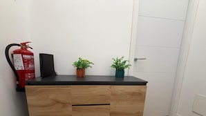 Um armário de madeira com superfície preta, um extintor de incêndio à esquerda e duas plantas em vasos sobre ele.