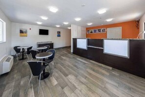 A modern office space with a reception area, several tables and chairs, and a flat-screen TV mounted on the wall. - 1 King Bed|Smoking, Micfridge (Greenville)