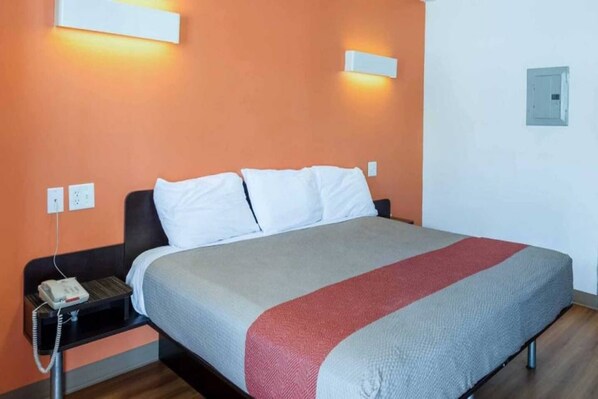 A hotel room with a bed, a nightstand, and a telephone. - 1 King Bed|Smoking, Micfridge (Greenville)
