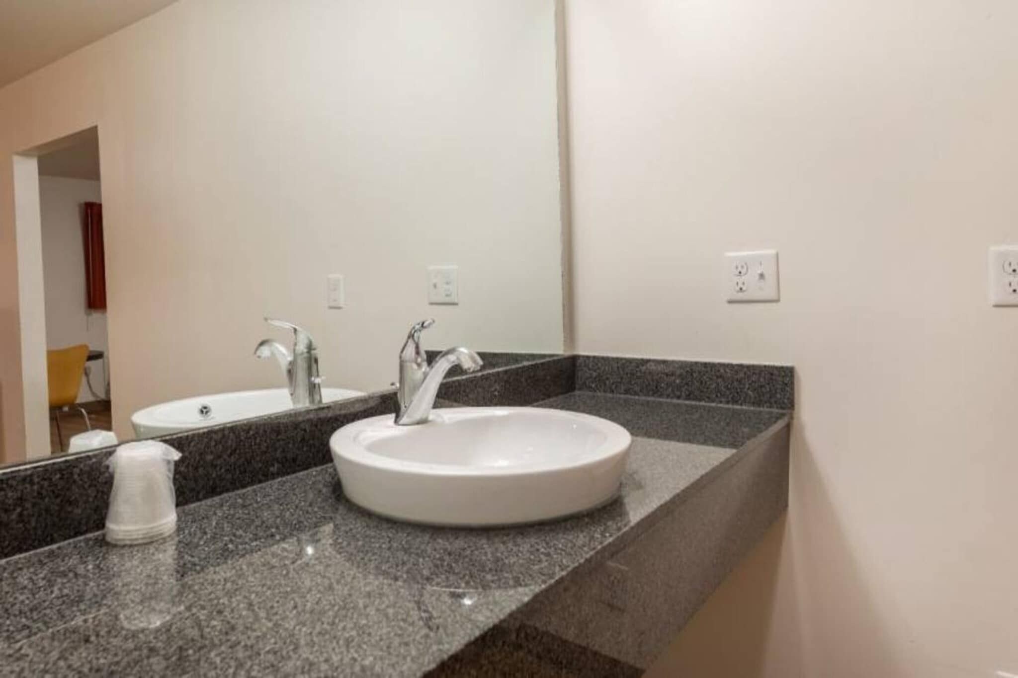 Ein Badezimmer mit zwei Waschbecken, einem Spiegel und einer Arbeitsplatte aus Granit.