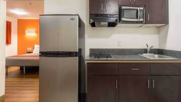 A compact kitchen with a refrigerator, microwave, and a sink.