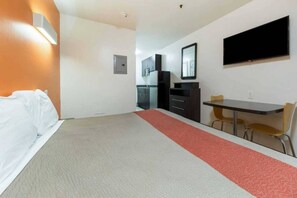 A hotel room with a bed, a desk, a chair, a TV, and a kitchenette. - 1 King Bed|Smoking, Micfridge (Greenville)