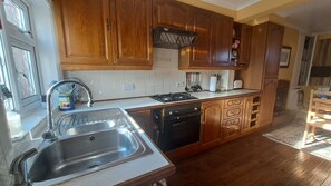 A kitchen with wooden cabinets, a stainless steel sink, a dishwasher, and a stove.