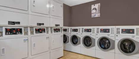 A laundry facility with multiple washing machines and dryers, arranged in rows.