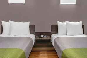 Une chambre d’hôtel avec deux lits, une table de chevet et une petite table.