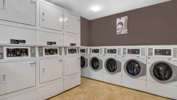 A laundry facility with multiple washing machines and dryers, arranged in rows.