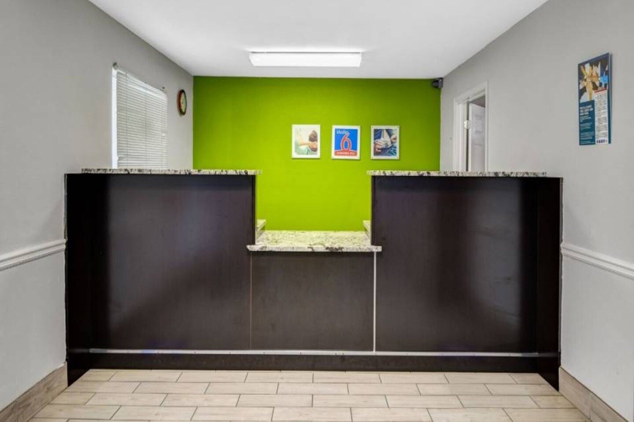 A hallway with a green wall, two black partitions, a tiled floor, and a door on the right.