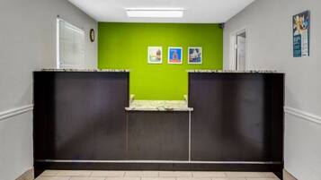 A hallway with a green wall, two black partitions, a tiled floor, and a door on the right.