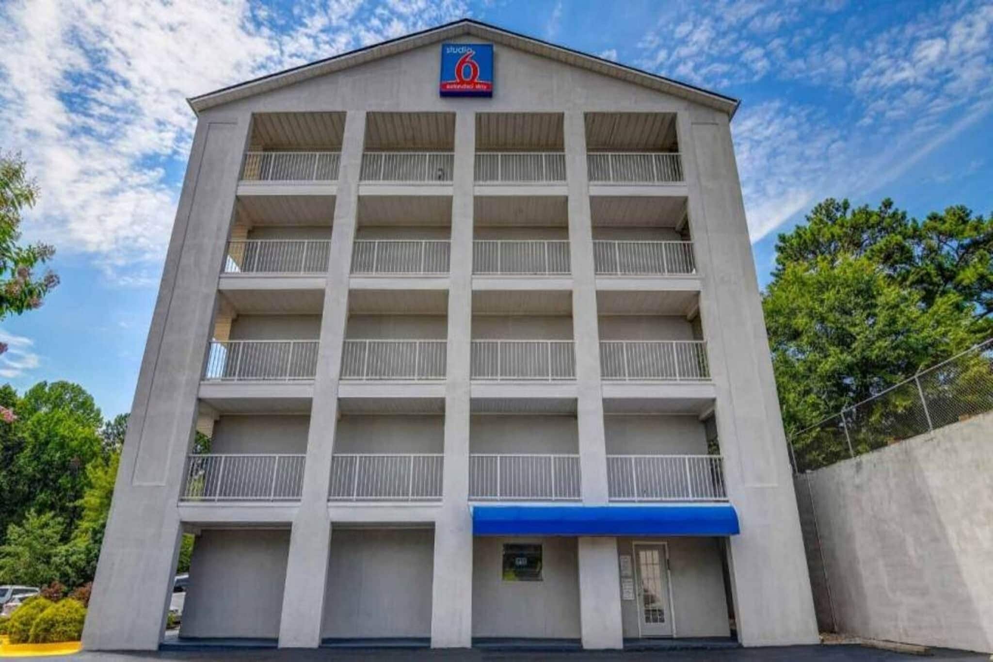 Edifício de vários andares com entrada central e toldo azul.