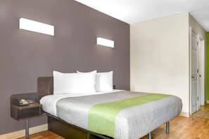 Une chambre d’hôtel avec un lit, une table de chevet et une petite table de nuit avec un téléphone.