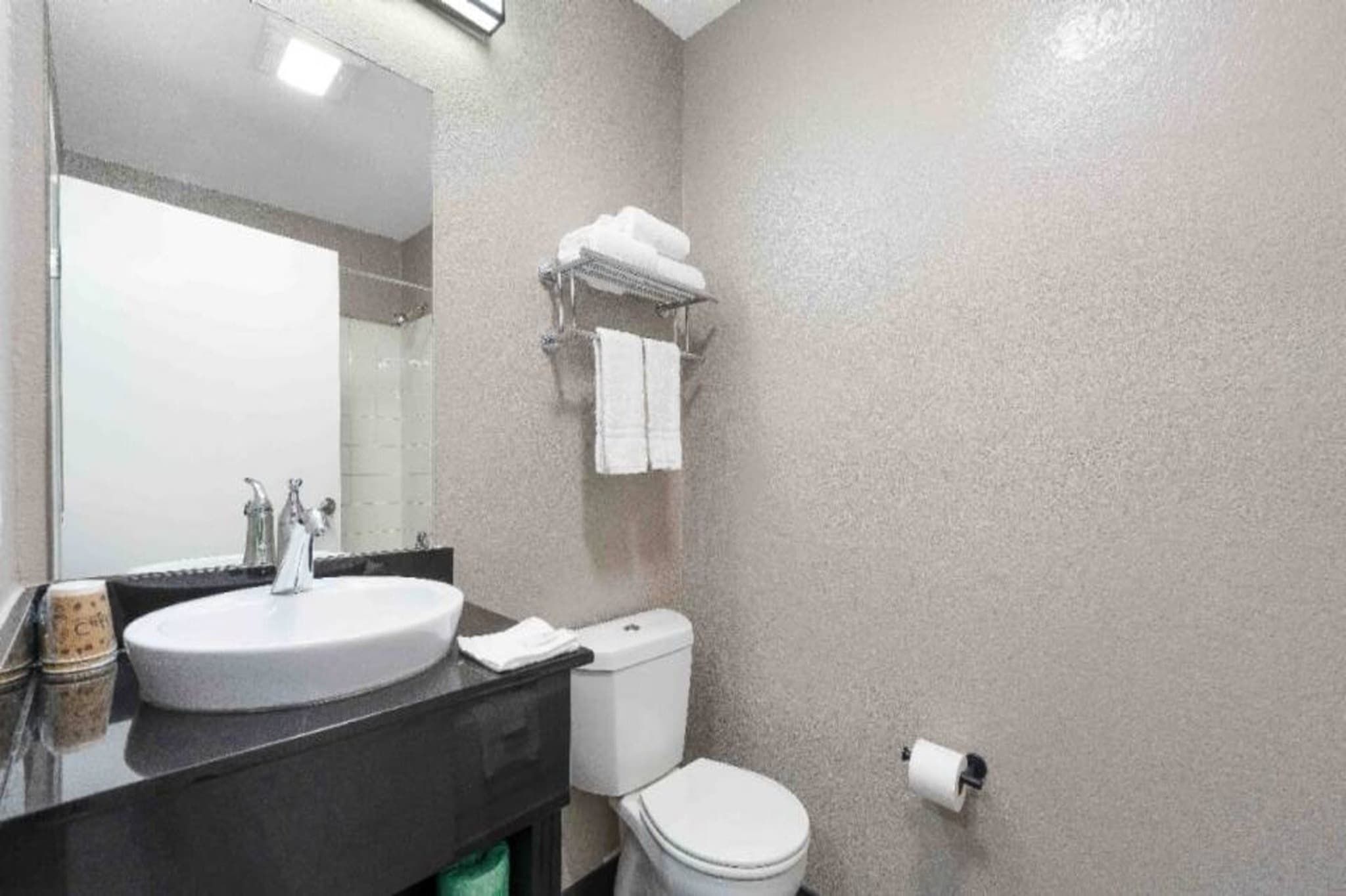 A bathroom with a sink, toilet, and a towel rack.