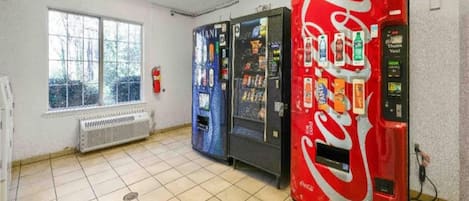 A room with a window, a radiator, and three vending machines.