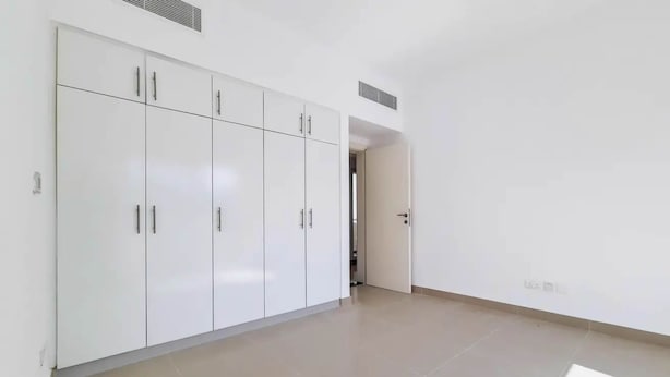 A room with a large wardrobe, a door leading to another room, and a tiled floor. - 5 bedroom villa with direct access to Montgomerie Golf - Perfect for families (Dubai)