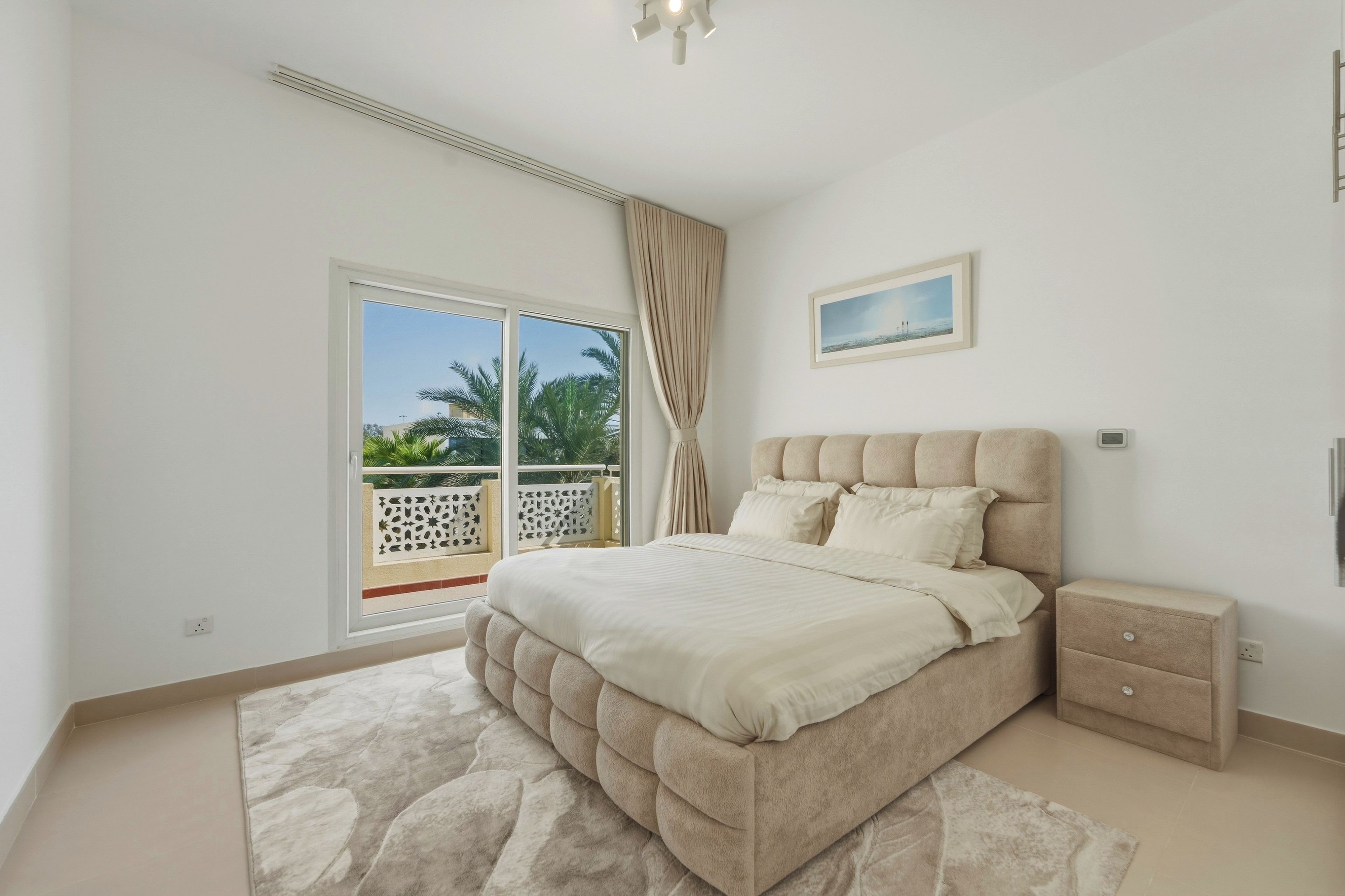 A bedroom with a bed, a nightstand, a window with a view, and a ceiling light.