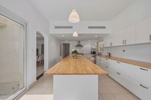 Une cuisine moderne dotée d’un îlot central, de meubles blancs et d’un éclairage suspendu.