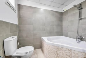 Une salle de bain avec des toilettes, une douche et une baignoire.