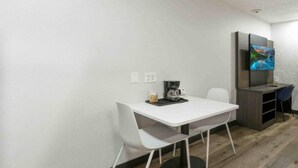 A small room with a white table, two white chairs, a coffee maker, and a television on a stand. - 2 Queen Beds | Non-Smoking (Tucker)