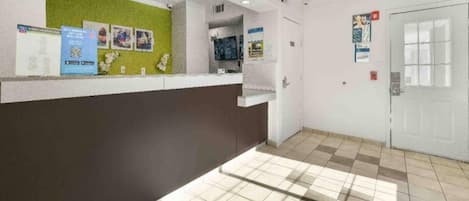 A reception area with a counter, a green wall, and an exit sign.