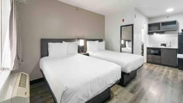 Een hotelkamer met twee bedden, een kitchenette en een badkamer.