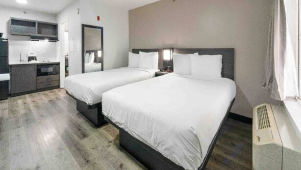 Een hotelkamer met twee bedden, een kitchenette en een badkamer.